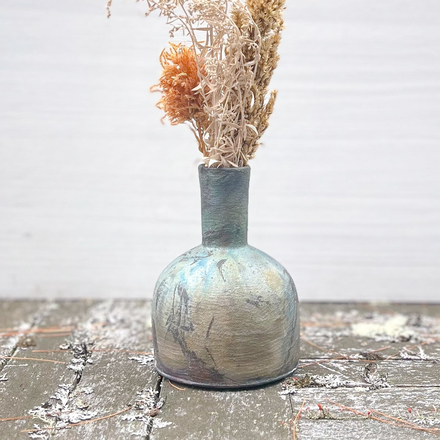 Ceramic vase with dried flowers on a textured surface